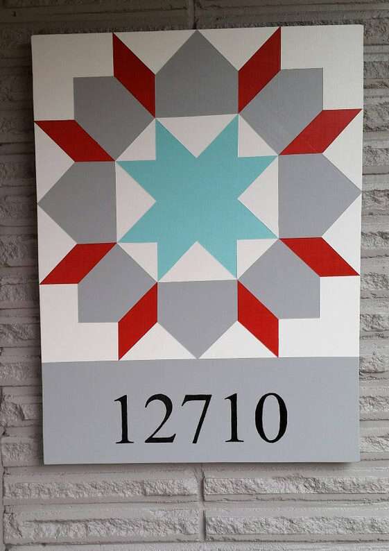 a barn quilt with the home address hanging on the wall.