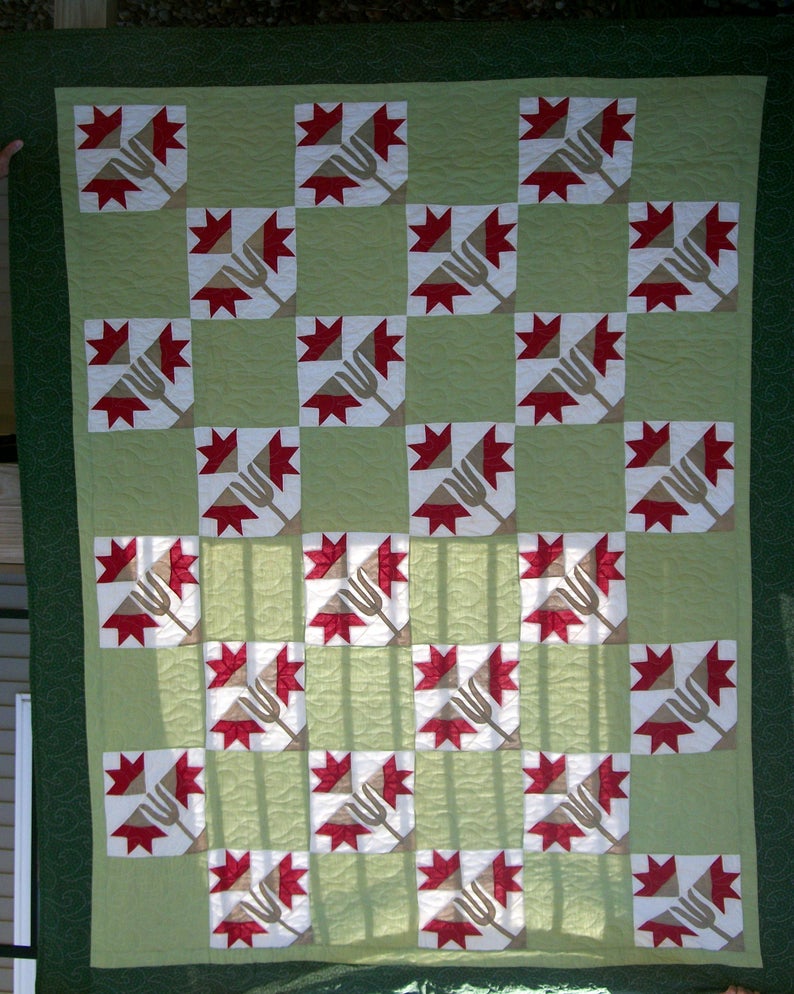 a red lilies quilt hung up by someone