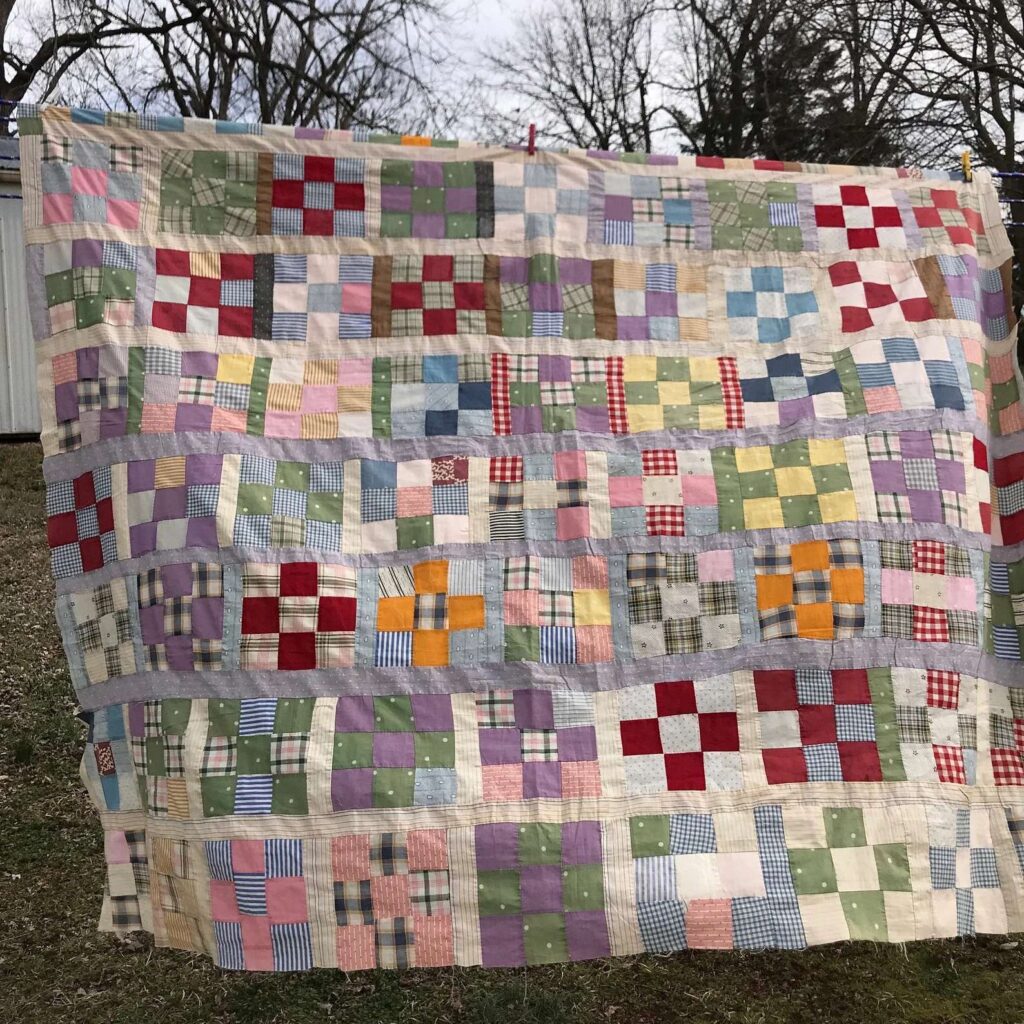 a colorful square quilt is hung on a string