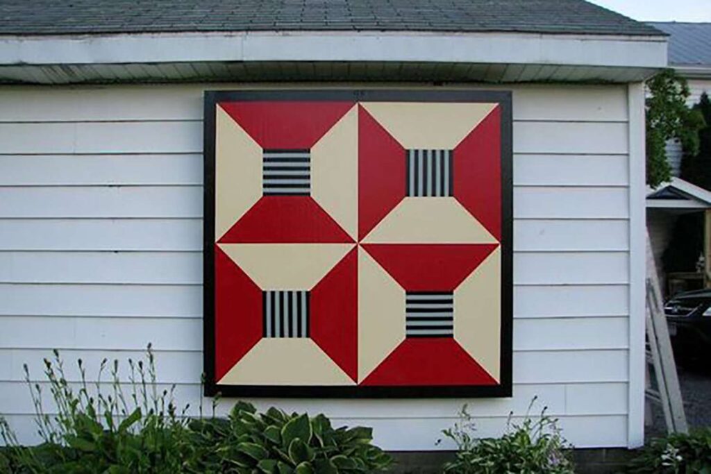 a barn quilt hanging on the white wall.