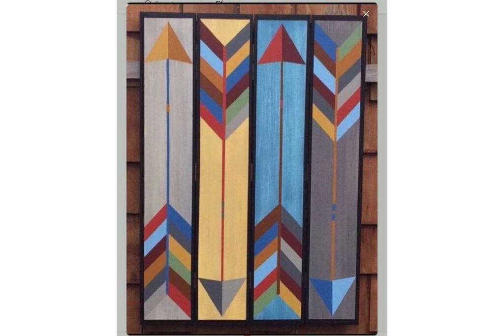 a vibrant arrow pattern barn quilt hanging on the wooden wall.