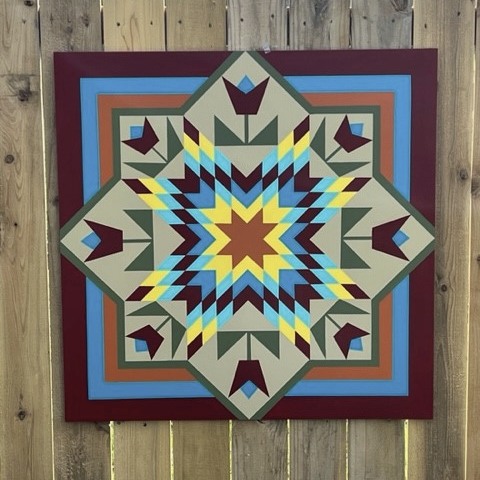 a flower barn quilt hanging on the wooden wall.
