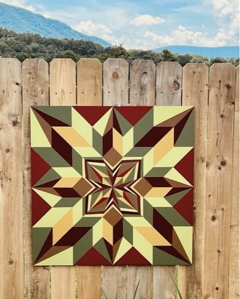 a colorful patterned barn quilt hanging on the wooden wall.