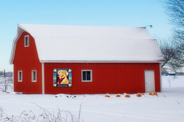 golden retriever barn quilt hanging on a red barn with snow background 