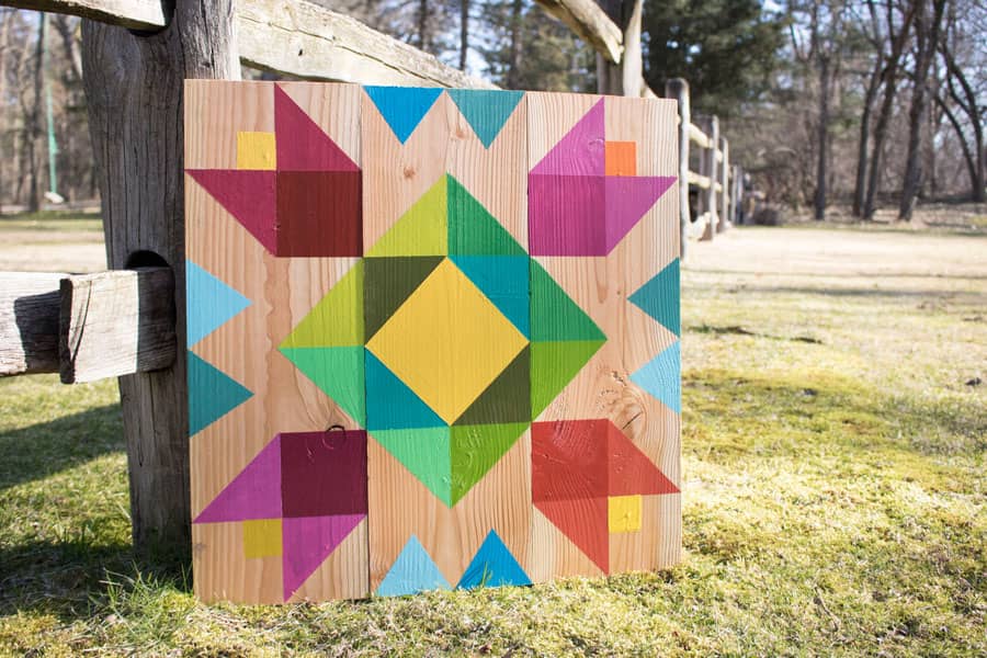 A natural wood barn quilt lying on the fence outdoor