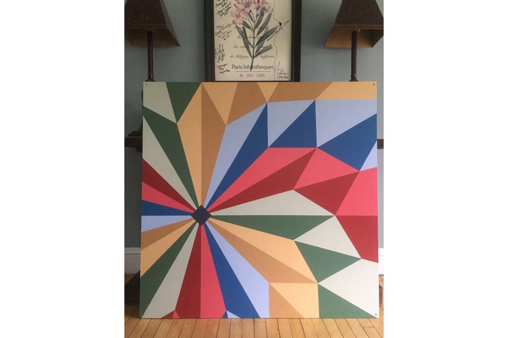 a colorful patterned barn quilt is placed on the floor