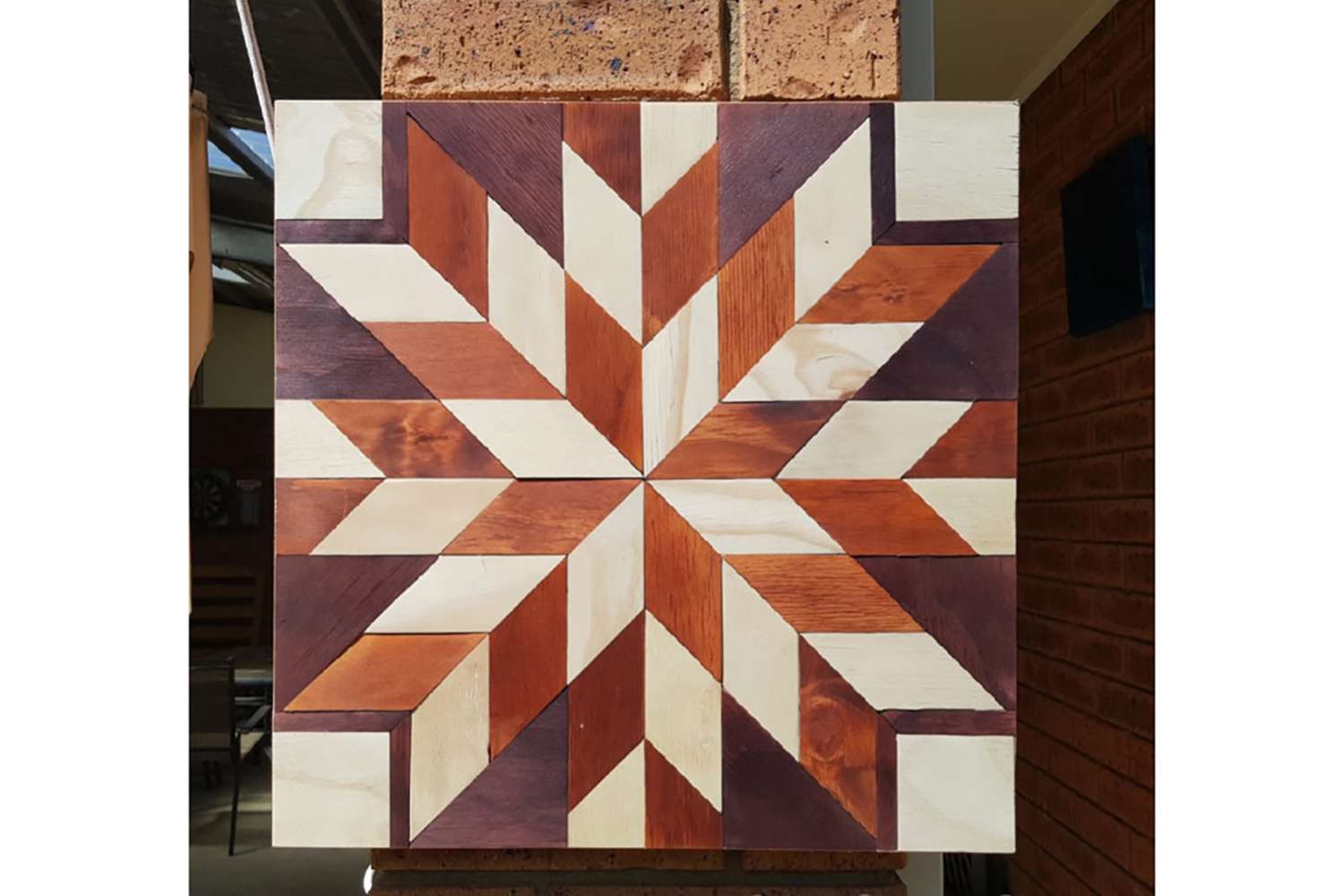 a stained multi-piece barn quilt is hanging on the pole