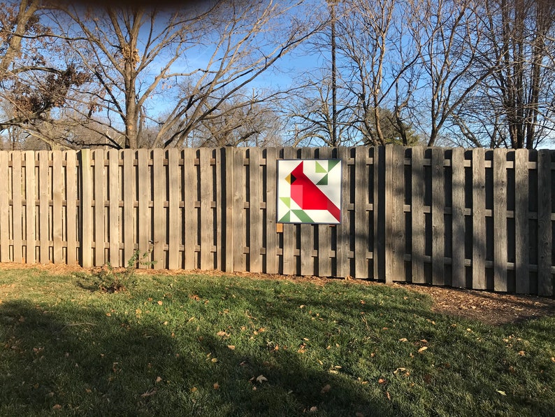 a barn quilt hanging on the wooden fence