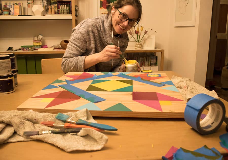 a girl is creating a new barn quilt.