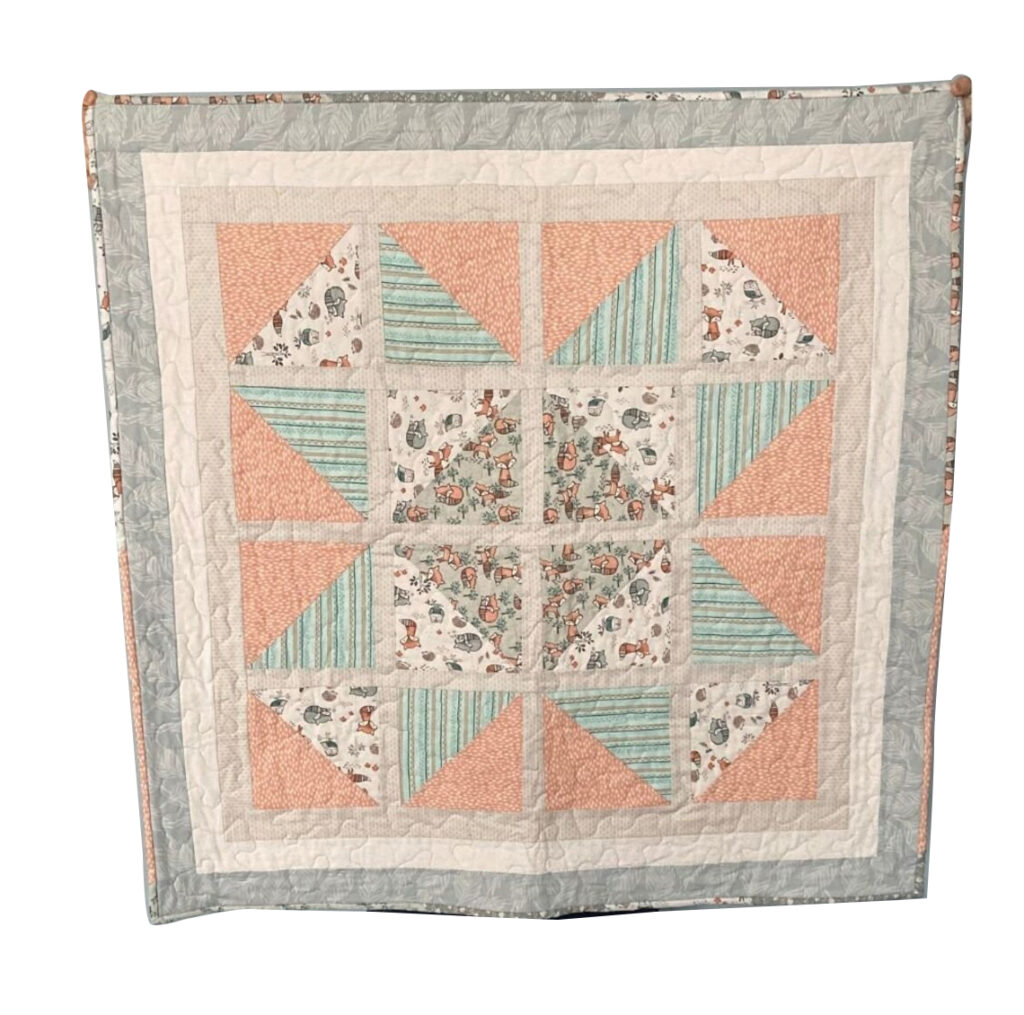 The baby quilt pattern features muted colors for warmth and comfort