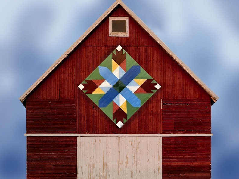 a bear paw star barn quilt hanging on the barn door.