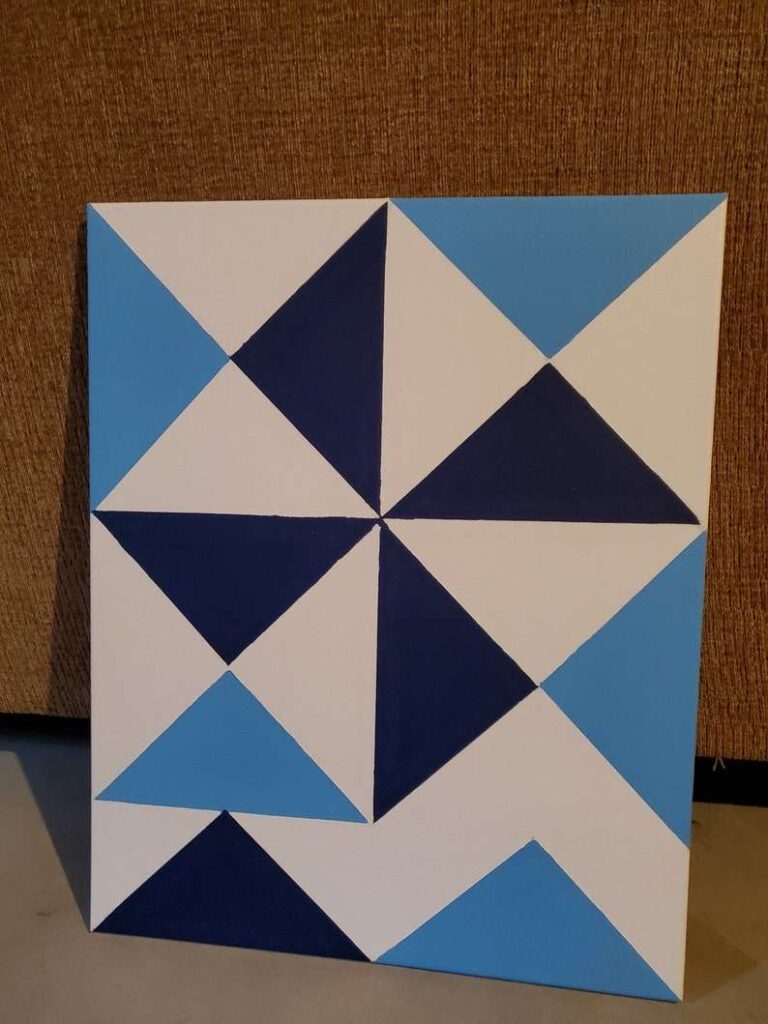 a blue barn quilt placed on the floor, leaning against the sofa back.