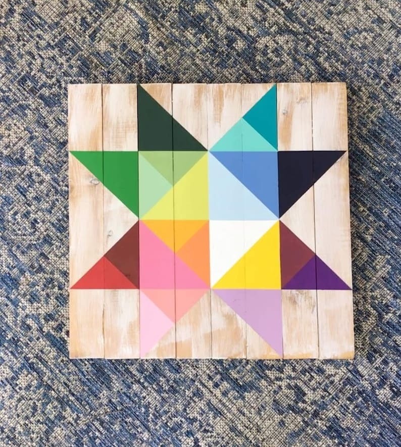 a small barn quilt with the multicolor star pattern laying on the rug.