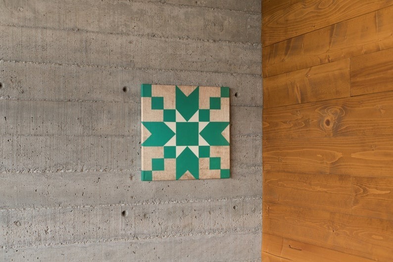 a small barn quilt with the teal star pattern hanging on the wall.