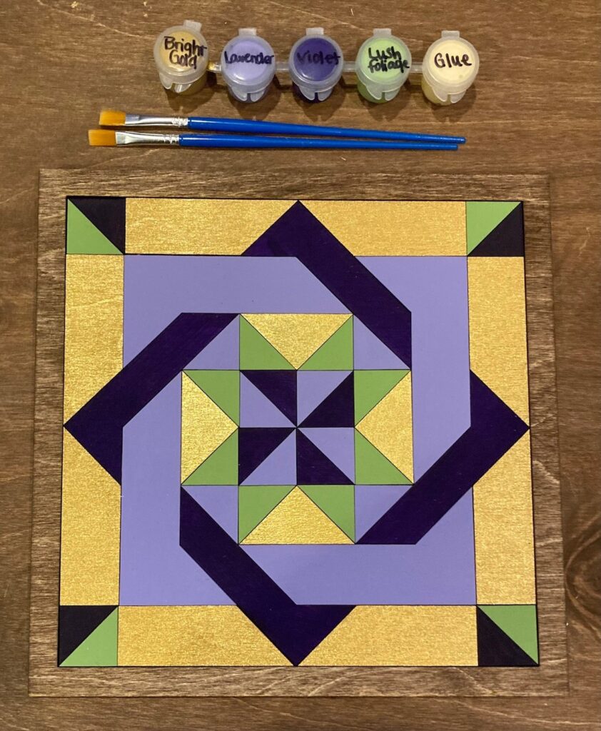 the barn quilt with four diamonds arranged side by side pattern placed on wooden surface