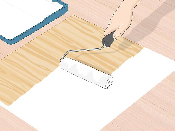 A hand is using a roller to paint a wooden panel