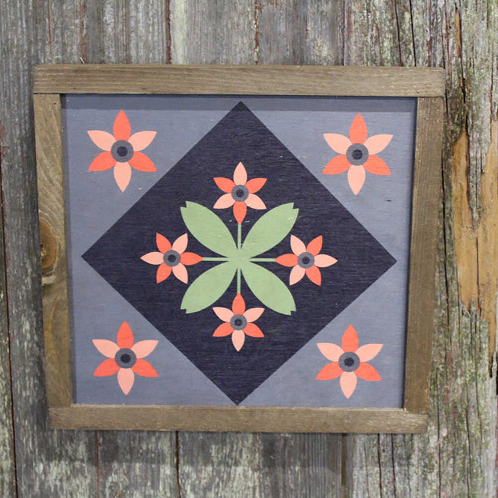 a barn quilt with small flowers pattern hanging on the wooden wall