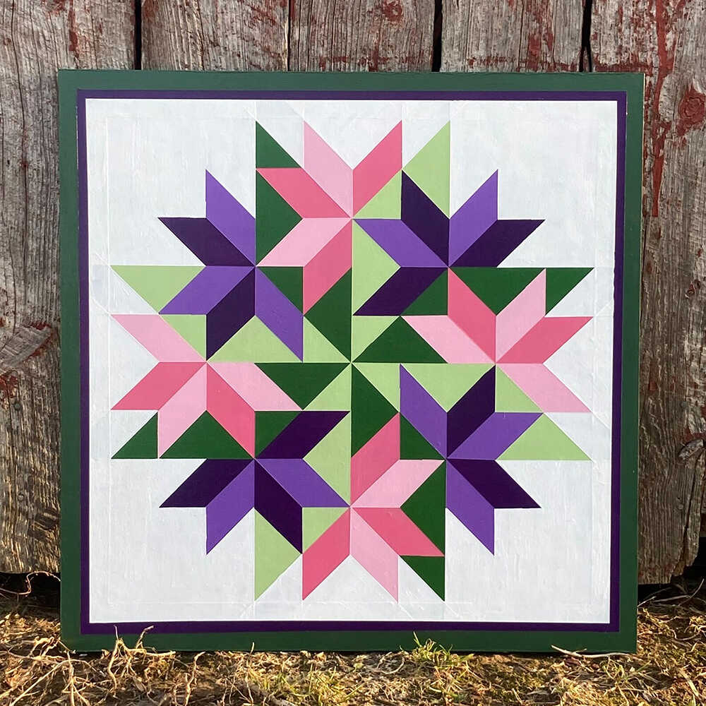a barn quilt with the hydrangeas pattern leaning against the wooden wall