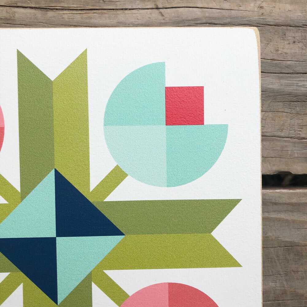 a corner of a barn quilt with four tulip flowers pattern laying on the wooden floor