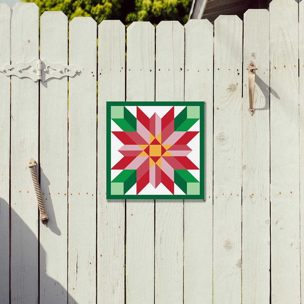 a barn quilt with red flower pattern hanging on the wooden fence