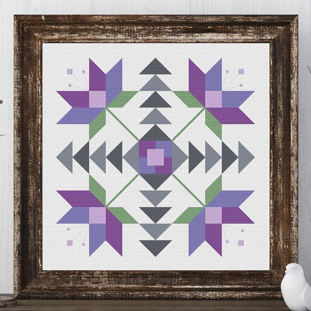 a barn quilt with purple flowers pattern laying on the wooden table