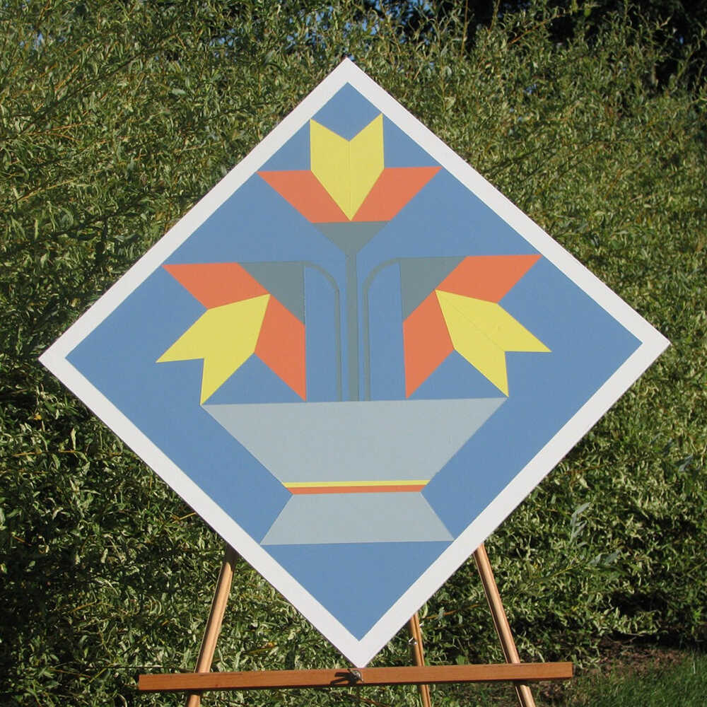 a barn quilt with lilies flower pot pattern placed on the wooden rack