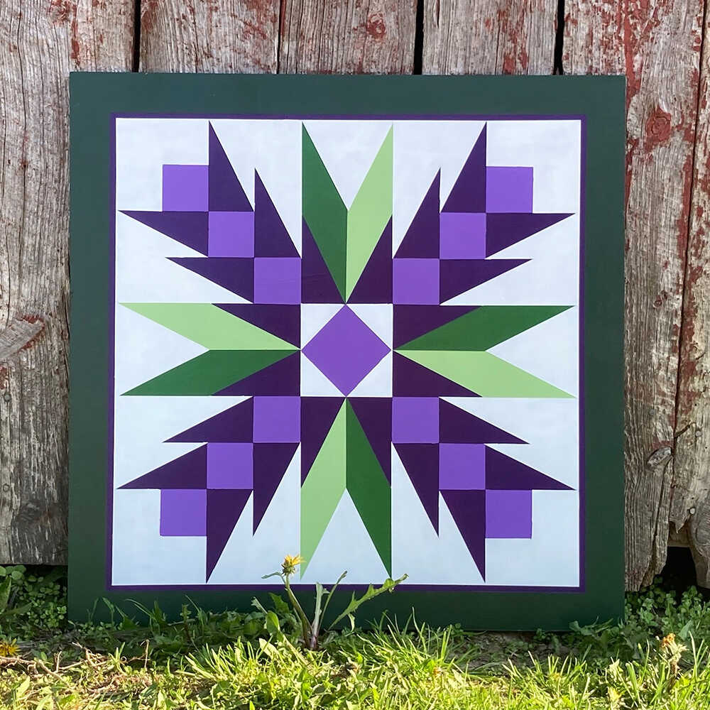 a barn quilt with purple flowers pattern leaning against the wooden wall.