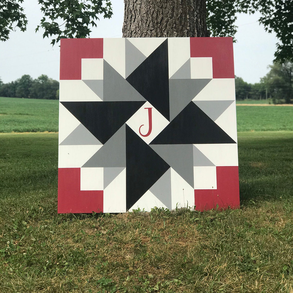 a barn quilt with pinwheel pattern and initials