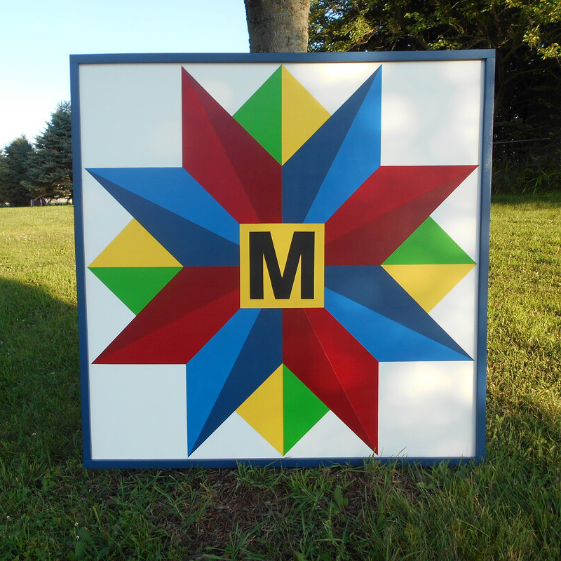 a barn quilt with blue and red star with initials