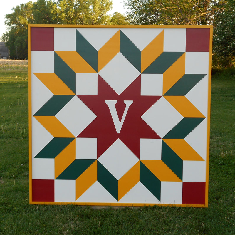 a barn quilt with red star and yellow flower pattern -white background