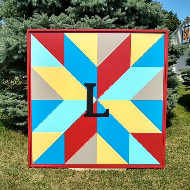 red, yellow and blue  star barn quilt with Initials placed in the garden
