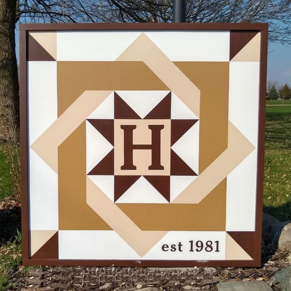 a barn quilt with an interlocking squares pattern leans against a black lamppost in the garden