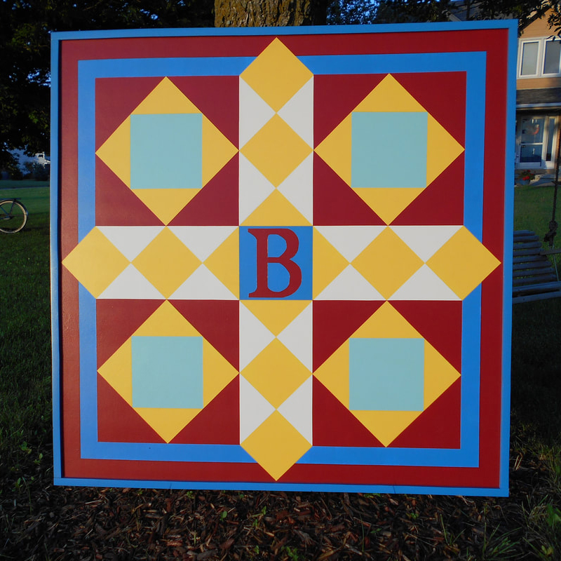 a barn quilt with yellow squares pattern and red background.