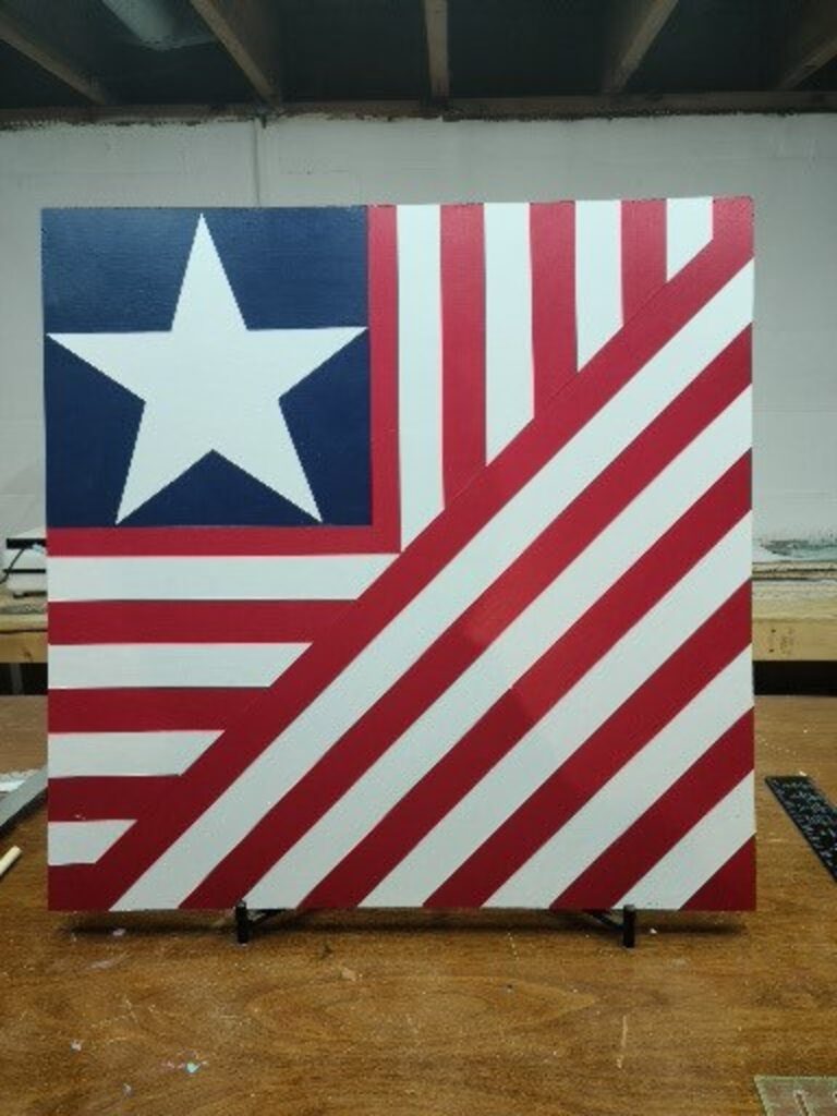a barn quilt in American Flag placed on the metal rack
