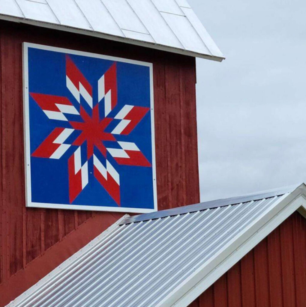 a barn quilt hanging on the barn