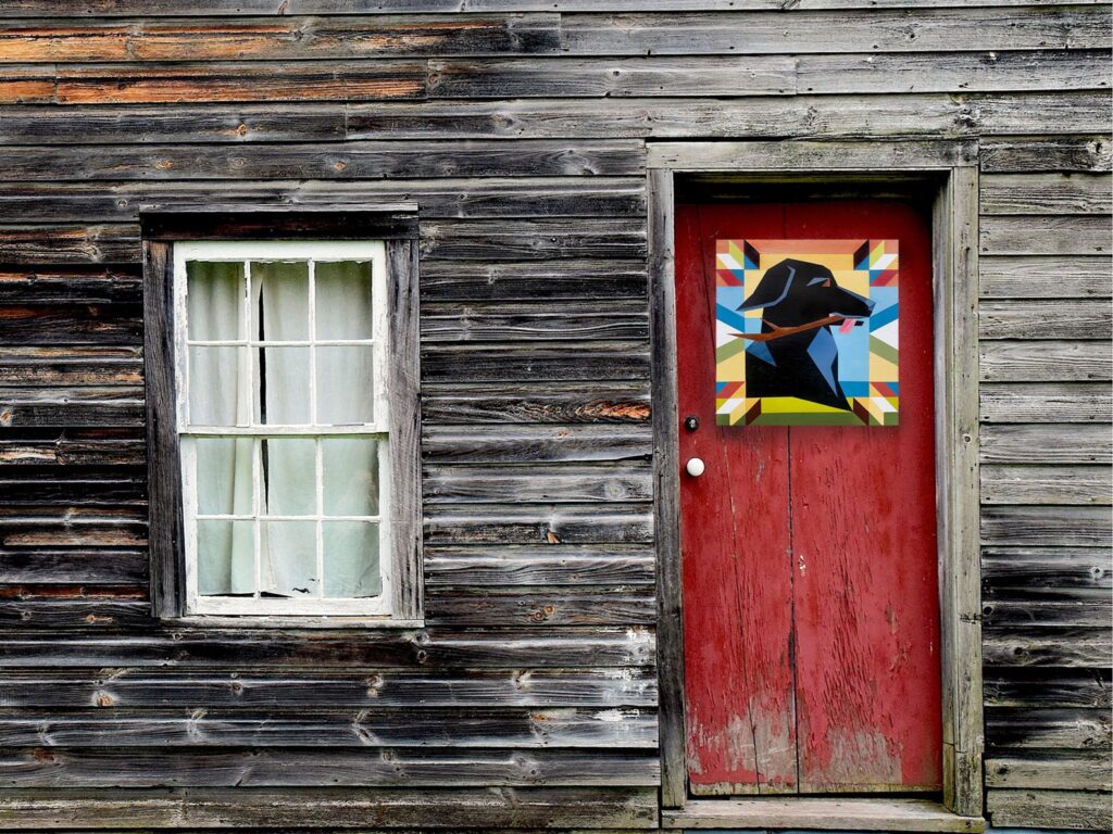 a black lab retriever barn quilt hanging on the door, next to the window
