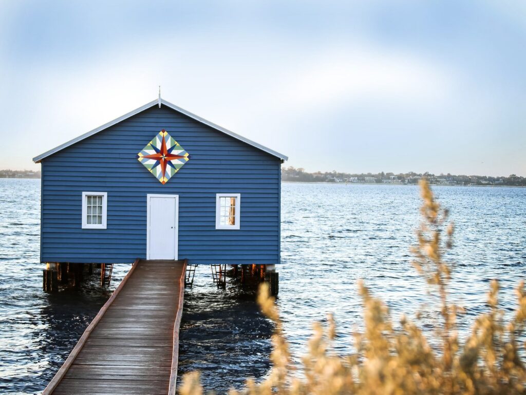 a mariner's compass barn quilt hanging on the barn in the river.