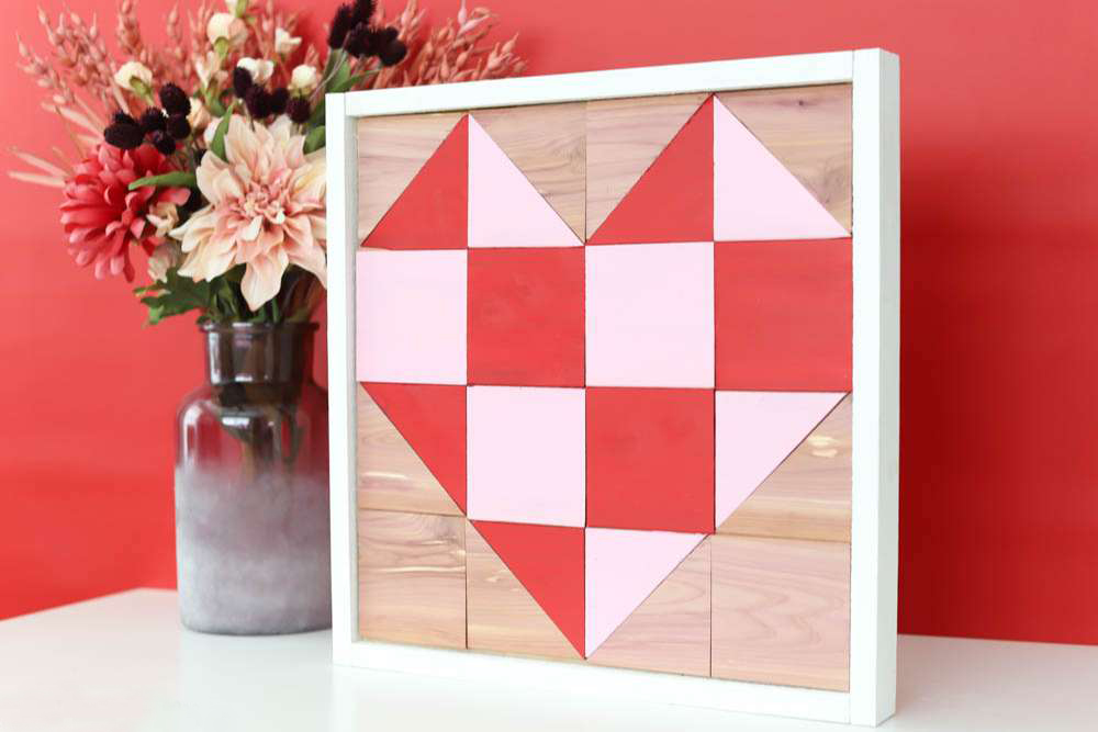 a pink heart barn quilt placed the top table, next to the flower case.