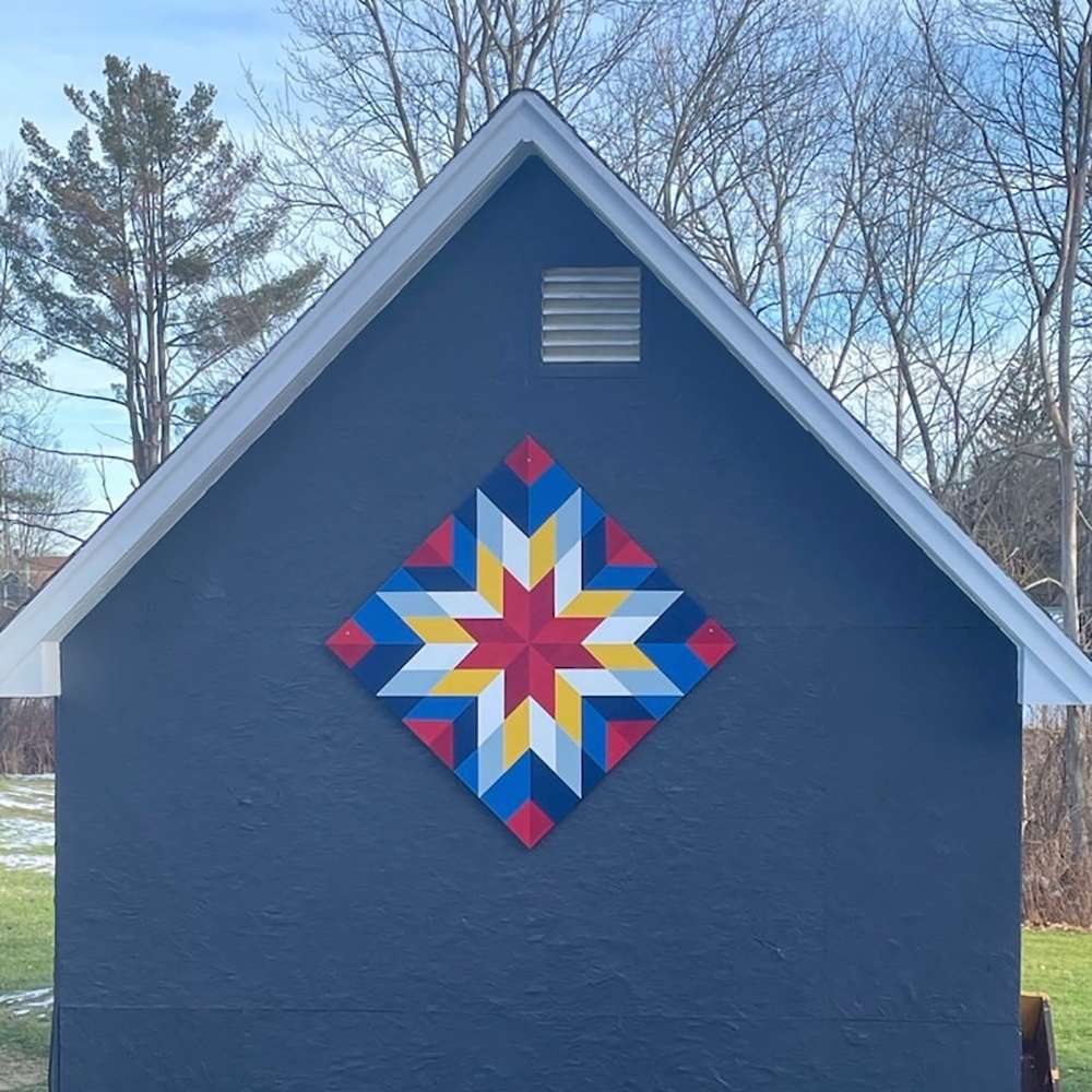 a yellow and red star barn quilt hanging on the barn.