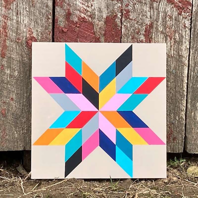 a barn quilt with colorful star pattern placed on the platform, leaning against wooden wall