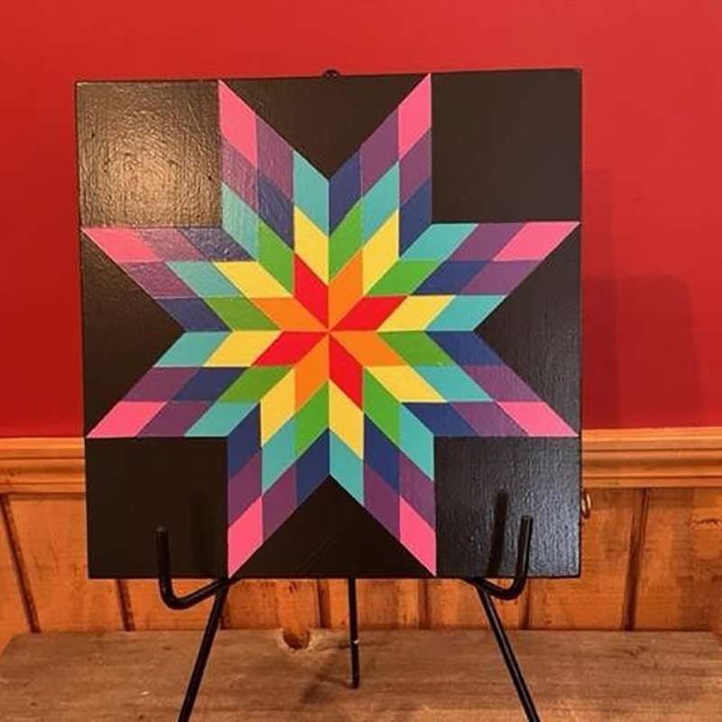 a barn quilt with colorful star pattern placed on the metal rack.