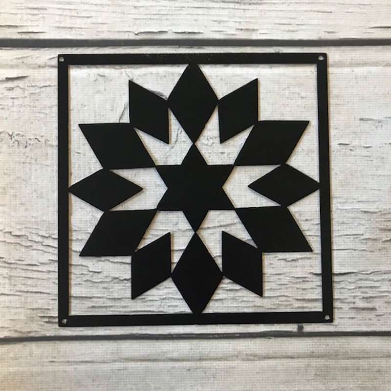 a black metal barn quilt laying on the wooden floor