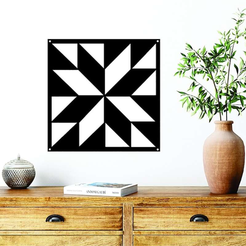 a black metal barn quilt hanging on the wall, above the wooden cabinet.