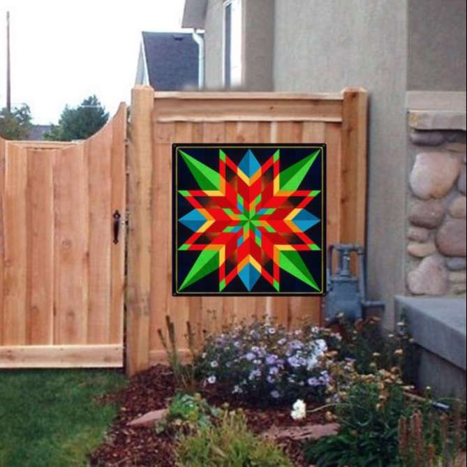 a barn quilt with colorful star pattern hanging on the wooden fence