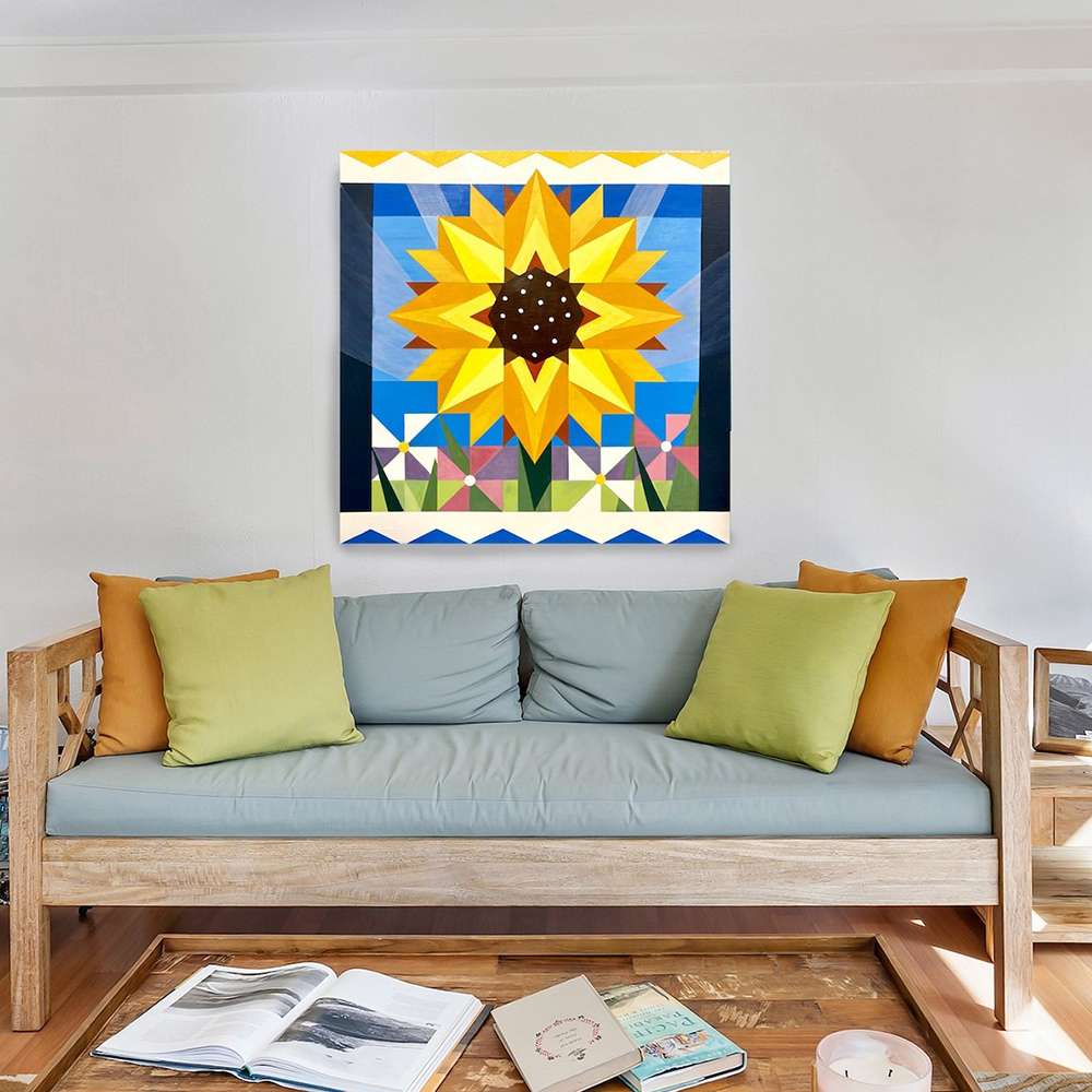 a sunflower barn quilt hanging on the wall, above a sofa