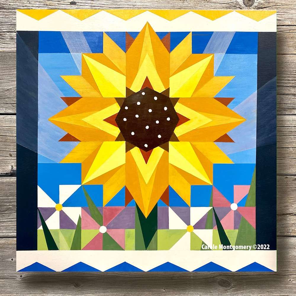 a sunflower barn quilt laying on the wooden floor