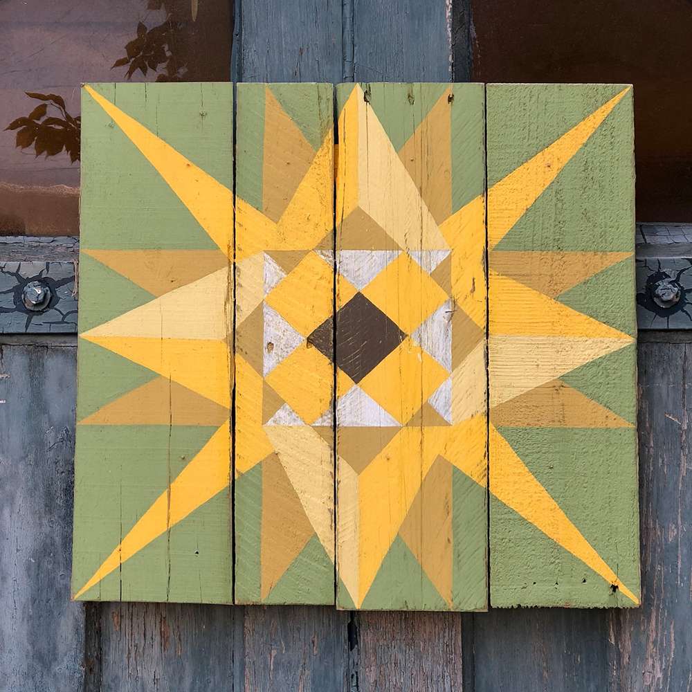 a sunflower barn quilt hanging on the barn