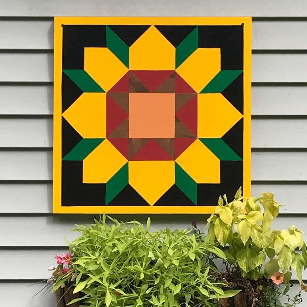 a barn quilt with the sunflower pattern hanging on the wall