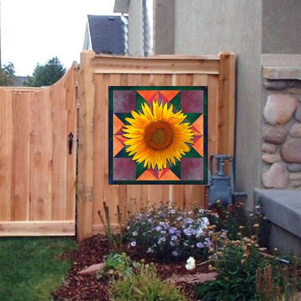 a sunflower barn quilt hanging on the wooden fence