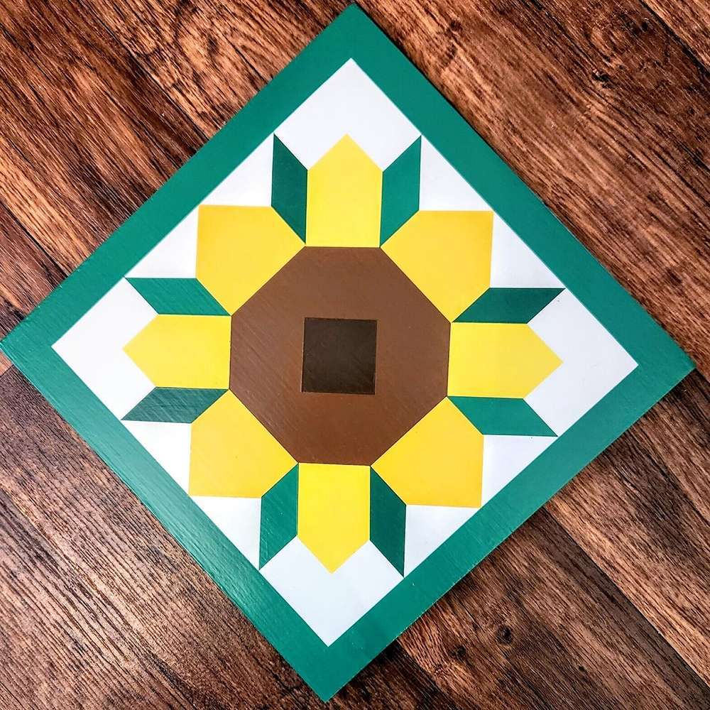 a sunflower barn quilt laying on the wooden floor